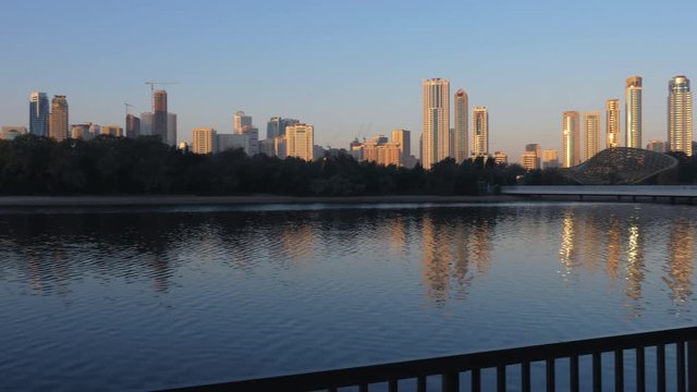 Panning through coastline of big city in UAE. Skyline with skyscrapers near lake.