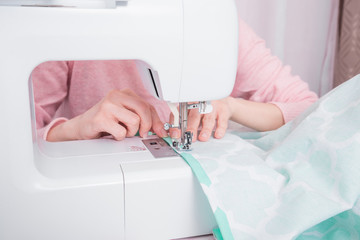 womans hadns workin on sewing machine