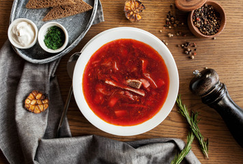 traditional Ukrainian dish borsch with greens and sour cream on a wooden table
