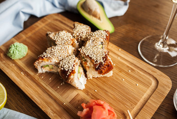Japanese sushi rolls with wasabi, ginger soy sauce and chopsticks and a glass of wine on a wooden board