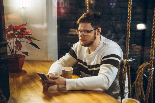 man drink tea and check his phone