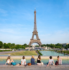 Eine Gruppe Touristen entspannt vor dem Eiffelturm in Paris, Frankreich - obrazy, fototapety, plakaty