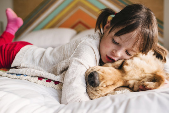 Girl lying on a bed with her golden retriever dog