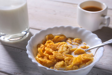Corn Flakes cereal in a bowl, glass with milk and cap with espresso coffee. Morning breakfast.