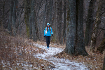 Young woman walking on snowy trail in winter park