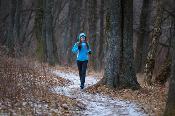 Young woman on trail running in winter park.