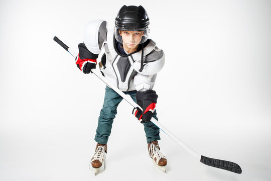 Young hockey player in safety gear with stick looking straight aggressively