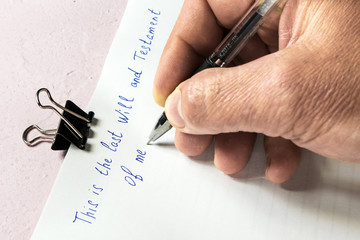 Writing a will. An elderly person writes on a blank sheet of paper