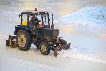 The tractor clears the ice on the road of the stadium for races from snow and unevennesses.
