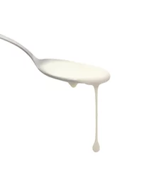 Gordijnen Fresh yogurt on a spoon isolated on white. Delicious yogurt drips from the spoon. Liquid drops © helen_tereshina
