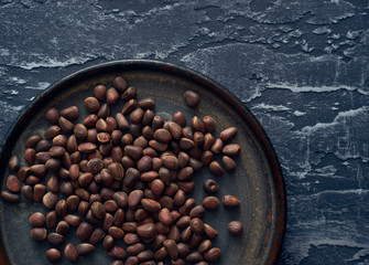 Delicious organic pine nuts in dark plate top view 