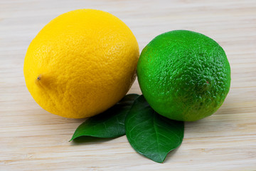 Fresh yellow lemon and green lime with leafs on wooden background
