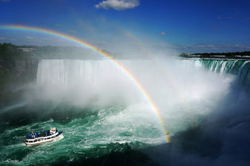Niagara Falls with spectacular rainbow on a sunny day. Sailing on the boat tour close to the Niagara Horseshoe Fall - Niagara, Canada