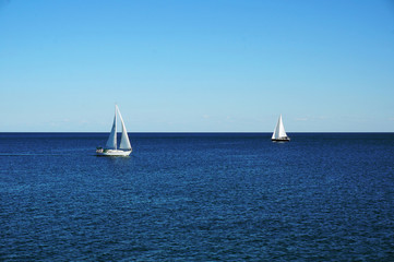 Two white sailing boats on a blue water of the Ontario lake - Toronto, Ontario, Canada