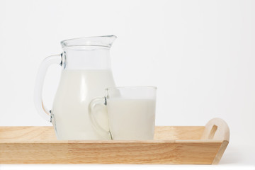 glass jug and a cup of milk on a wooden tray