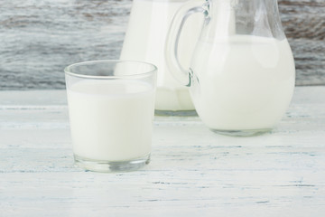 Milk in the glass jugs, white wooden background