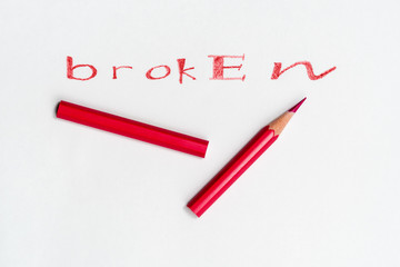 Broken two piece red pencil on white paper