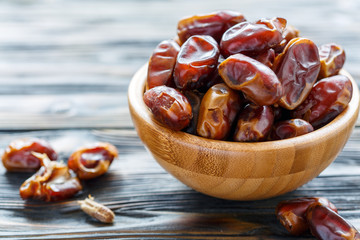 Dried date fruit in a wooden bowl.