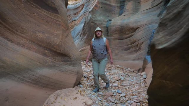 Woman Hiking On Dry River Gorge With Smooth And Wavy Rocks Of The Canyon 4K