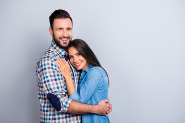 Portrait of beautiful, cheerful, positive, nice couple in shirt enjoying hug with each other, looking at camera over grey background