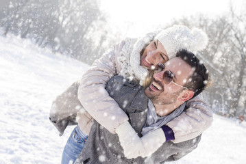 Happy smiling couple enjoying outdoor on snowy winter day