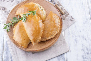 Fresh homemade pies for breakfast. Portion pies. On a wooden plate and on a white background. Free space for text or advertising.