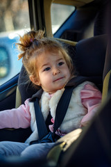 happy toddler girl buckled into her car seat.