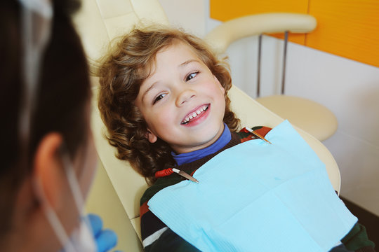 A cute, curly-haired child indulges and grimaces in a dental chair