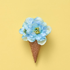 Ice Cream Cone with Bouquet of Flowers. Trendy fashion Style. Spring Summer Floral concept. Creative Minima on Yellow. Blue Flower, Vanilla Color. Art Vintage