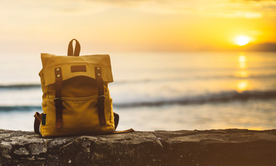 Hipster hiker tourist yellow backpack closeup on background blue sea enjoying sunset ocean horizon,...