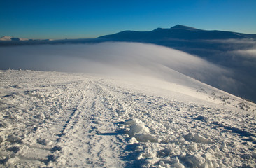 Fototapeta na wymiar Winter snowy landscape of mountains in background of blue sunny sky