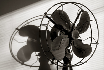 Antique Fan With Light Streaming Through the Window Blinds. A film noir take on a classic antique cooling fan with shadows and light projected onto the rear wall.
