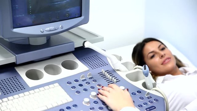 Medical exam of a young woman by ultrasound equipment