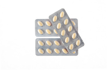 three plates of yellow pills on white isolated background