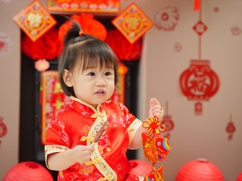 Chinese baby girl  with traditional dressing up and "FU" means "lucky" greeting card.some "FU" means "lucky"greeting card on the wall
