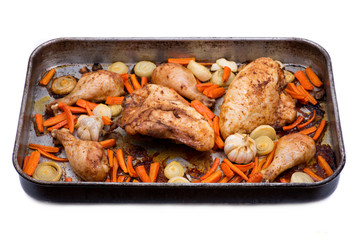 Roasted chicken, carrots, onion and garlic in metallic roaster oven pan