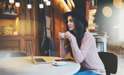 an attractive girl with long black hair ponders a new project during a coffee break sitting at a...