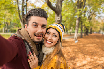 Beautiful couple taking a selfie at a park in autumn