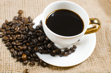Grains of black roasted coffee and a cup of coffee