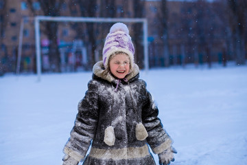 A cute little girl covered with snow has fun in winter park, wintertime