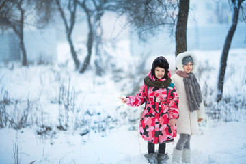Fototapeta na wymiar two little girls playing outdoors during strong snowfall. Active leisure with children in winter on cold days.