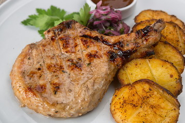 Steak on a bone with potatoes and sauce