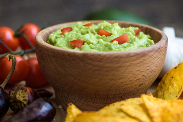 Guacamole in Wooden Bowl with Tortilla Chips and Ingredients