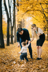 Naklejka na ściany i meble Family playing in autumn park having fun