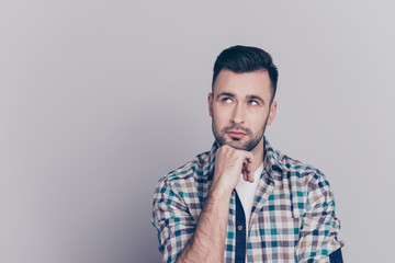 Fototapeta premium Portrait of attractive, thoughtful man holding arm on chin, having doubts, meditating, looking at copy space, standing over grey background