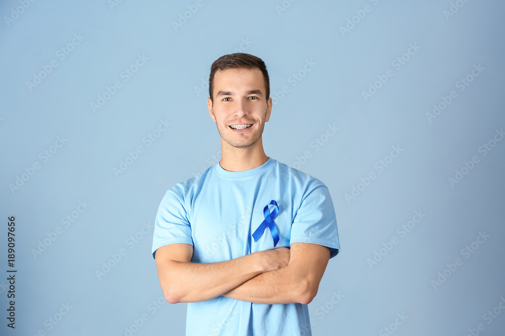 Poster Young man wearing t-shirt with blue ribbon on color background. Prostate cancer awareness concept