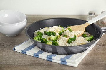 Frying pan with rice and broccoli on kitchen table