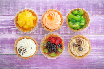 Assortment of tasty tartlets on wooden background, top view