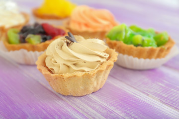 Tasty tartlet with whipped cream on wooden background