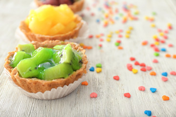 Tasty tartlet with kiwi pieces on wooden background